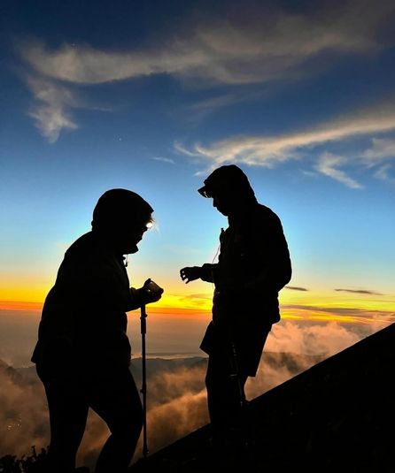 Hikers at sunrise over clouds